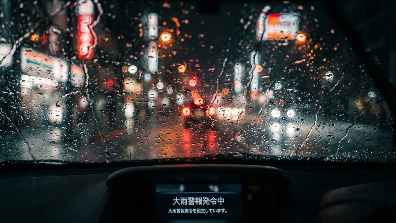 夜の雨道でフロントガラスがギラつき、対向車のライトで視界が悪くなっている様子